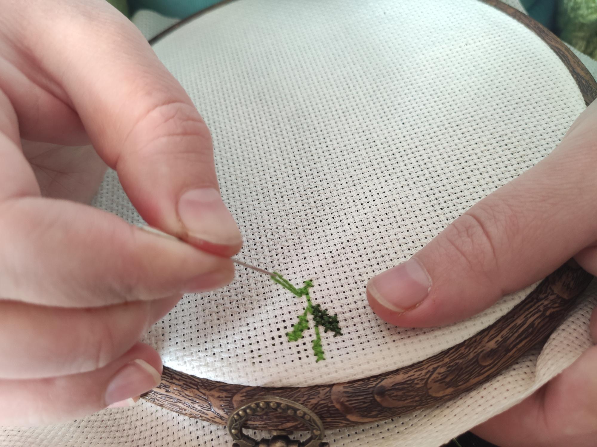 Hand holding embroidered linen with floral motif